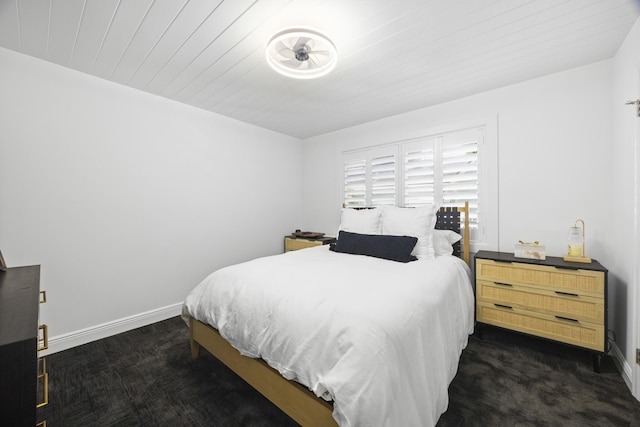 bedroom with dark carpet, wooden ceiling, and baseboards