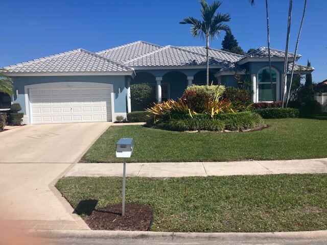 view of front of home with stucco siding, a front yard, a garage, driveway, and a tiled roof