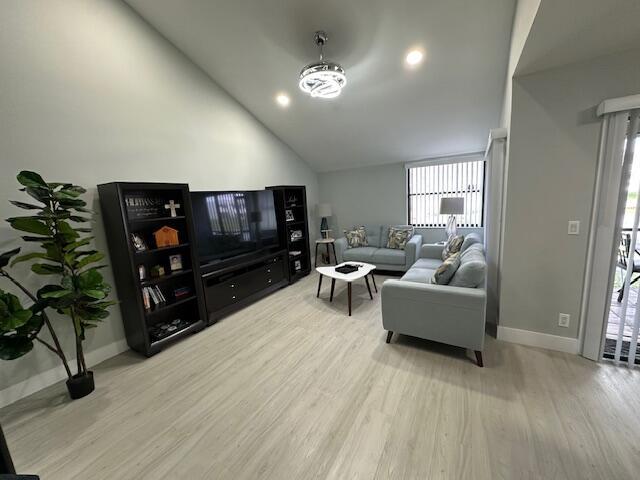 living room featuring lofted ceiling, baseboards, and wood finished floors