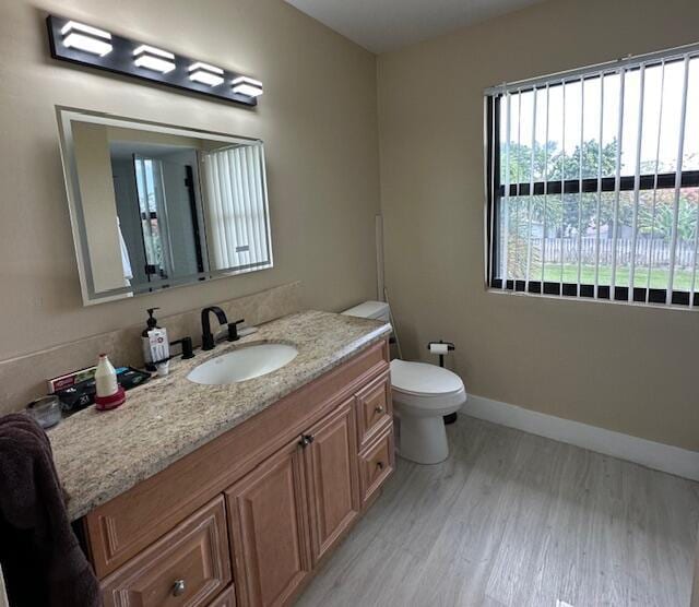 bathroom with vanity, wood finished floors, toilet, and baseboards