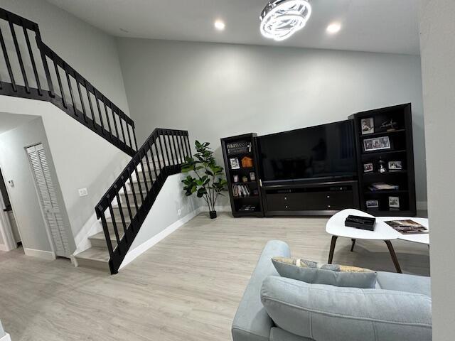 living area with baseboards, wood finished floors, a high ceiling, stairs, and recessed lighting