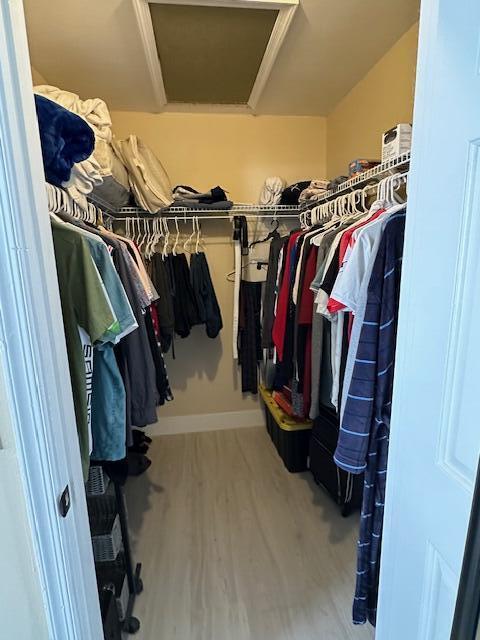 walk in closet featuring wood finished floors and attic access