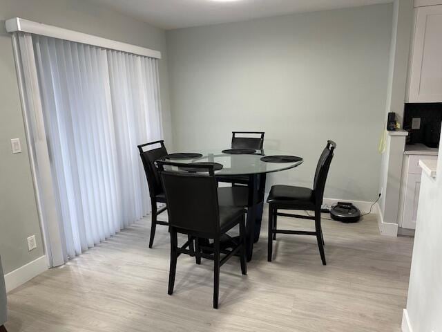 dining space with baseboards and light wood-style floors