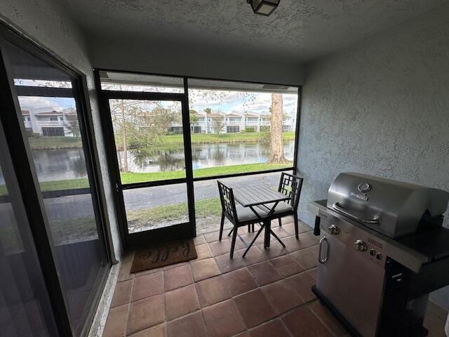 sunroom featuring a water view