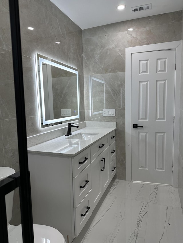 bathroom with marble finish floor, visible vents, and tile walls