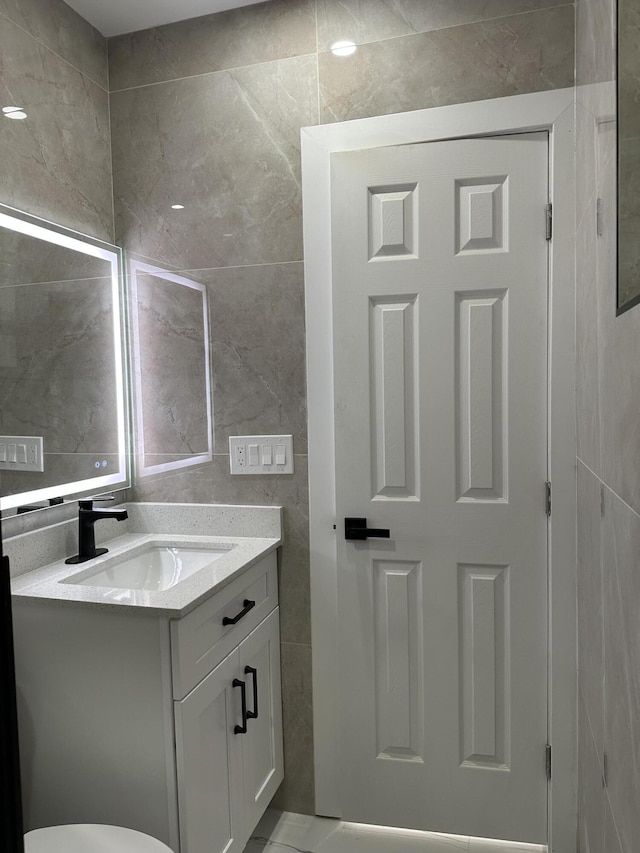 half bath with vanity and tile walls