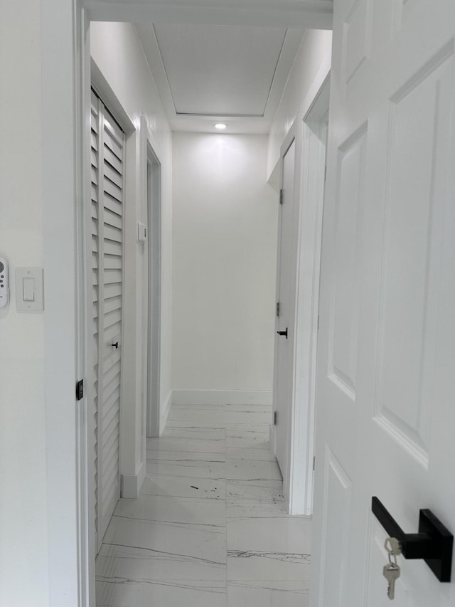 hallway featuring marble finish floor and baseboards