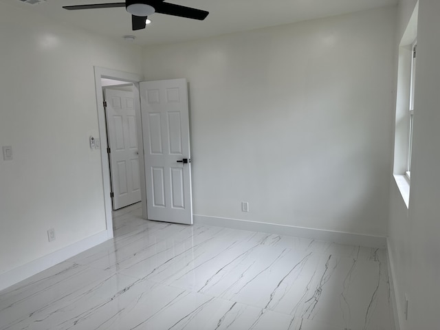 spare room featuring marble finish floor, visible vents, baseboards, and a ceiling fan