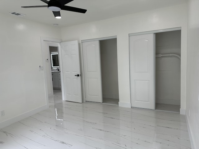 unfurnished bedroom featuring multiple closets, marble finish floor, visible vents, and baseboards