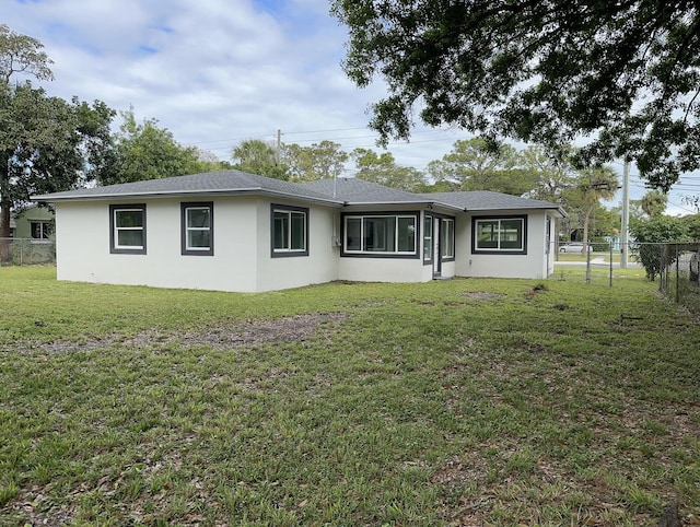 rear view of property with stucco siding, a lawn, and fence