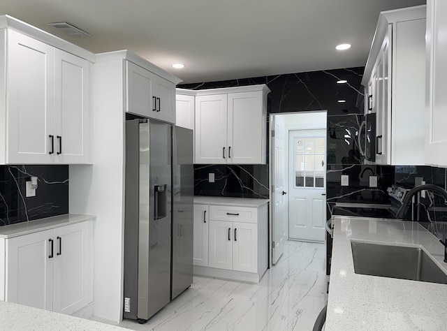 kitchen featuring marble finish floor, visible vents, white cabinets, a sink, and stainless steel fridge with ice dispenser