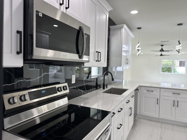 kitchen featuring a sink, marble finish floor, stainless steel appliances, white cabinetry, and backsplash