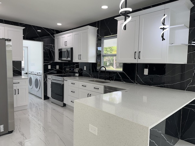 kitchen featuring open shelves, a peninsula, stainless steel appliances, separate washer and dryer, and a sink