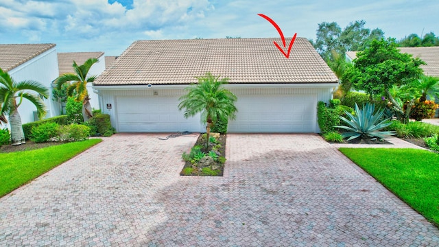 view of front of home featuring decorative driveway, a tiled roof, and an attached garage