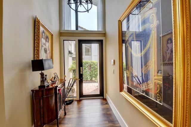 foyer featuring dark wood-style flooring, a towering ceiling, and baseboards