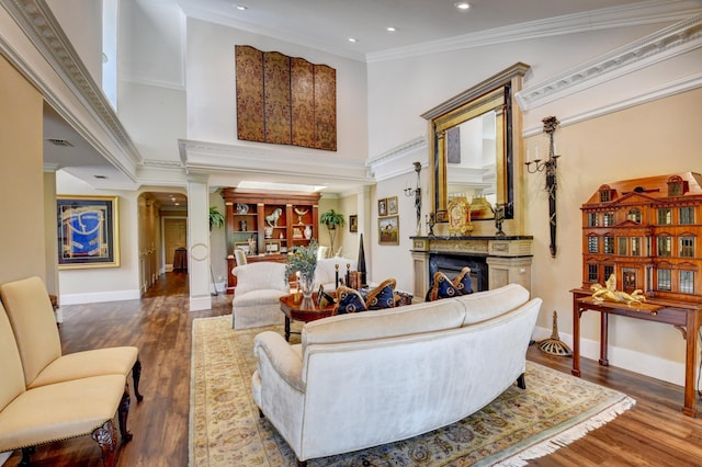 living room featuring ornamental molding, a fireplace, ornate columns, and wood finished floors