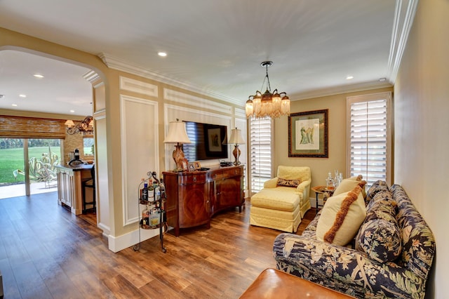 living room with arched walkways, recessed lighting, ornamental molding, wood finished floors, and a chandelier