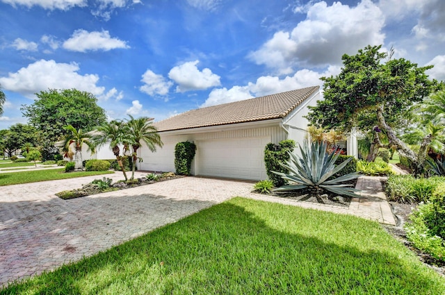 view of front of house featuring a garage, a front yard, decorative driveway, and a tiled roof