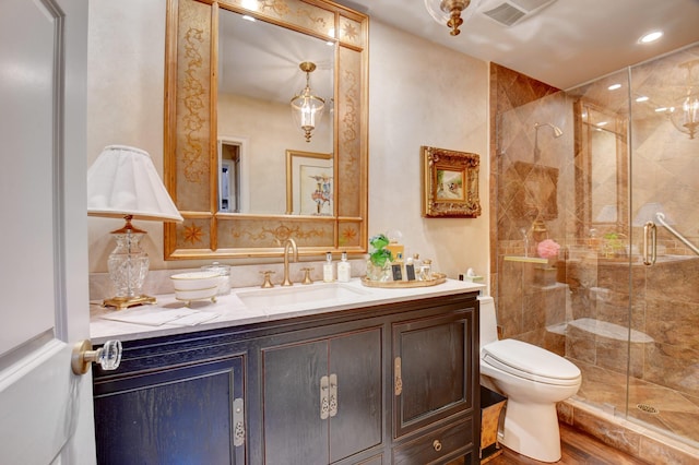 bathroom featuring visible vents, toilet, a shower stall, vanity, and wood finished floors