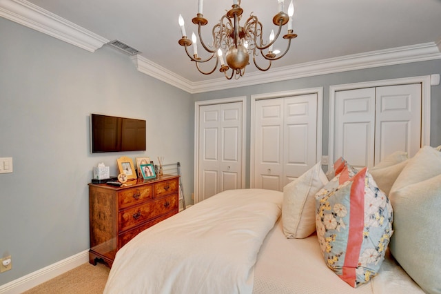 carpeted bedroom with a chandelier, visible vents, baseboards, two closets, and crown molding