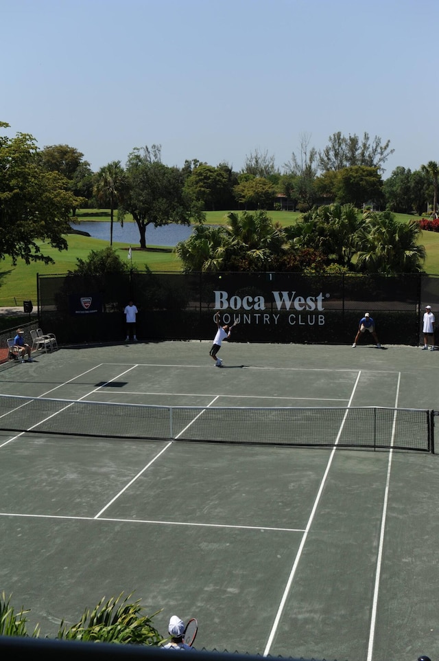 view of sport court with a water view and fence