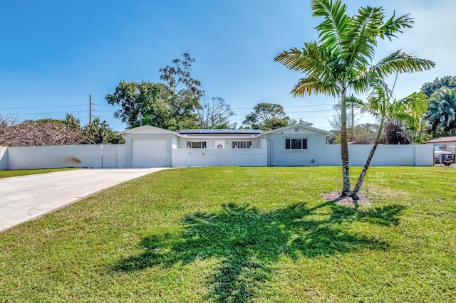 ranch-style home with an attached garage, solar panels, fence, driveway, and a front lawn