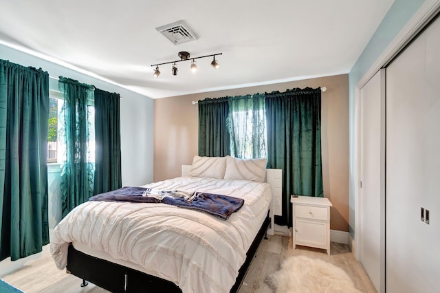 bedroom featuring light wood-style floors, a closet, visible vents, and baseboards