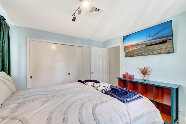 bedroom with rail lighting, visible vents, and a closet