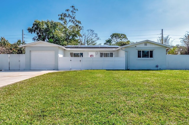 single story home featuring a fenced front yard, a garage, solar panels, and driveway