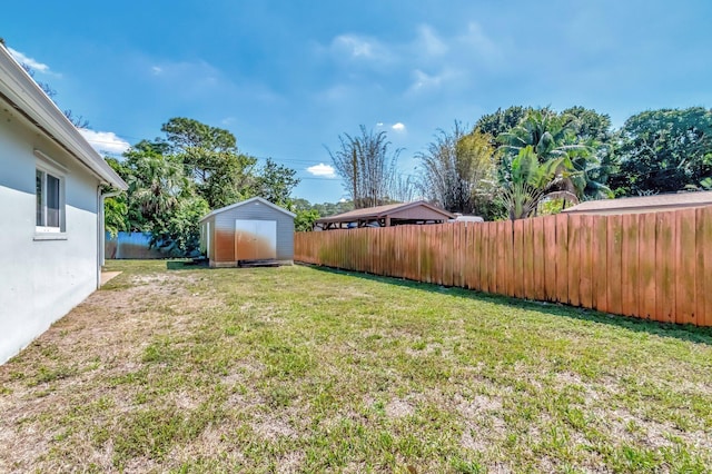 view of yard featuring an outbuilding, a fenced backyard, and a storage shed