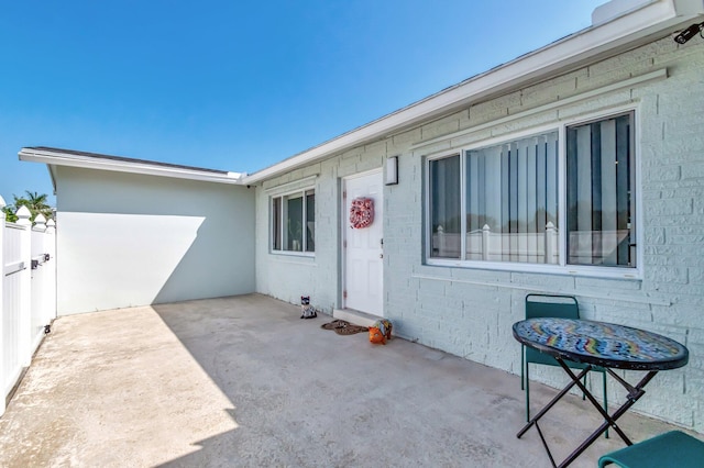 property entrance with brick siding, a patio area, and fence