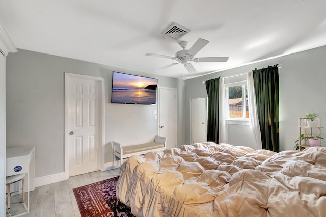 bedroom featuring ceiling fan, light wood finished floors, visible vents, and baseboards