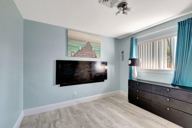 unfurnished bedroom with visible vents, light wood-style flooring, and baseboards