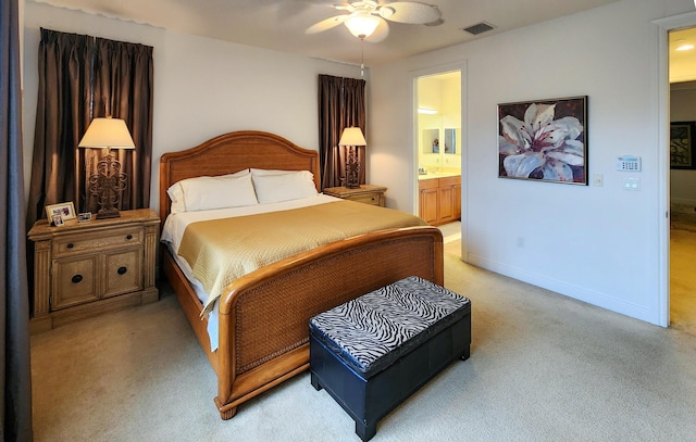 bedroom with a ceiling fan, baseboards, visible vents, ensuite bathroom, and light colored carpet