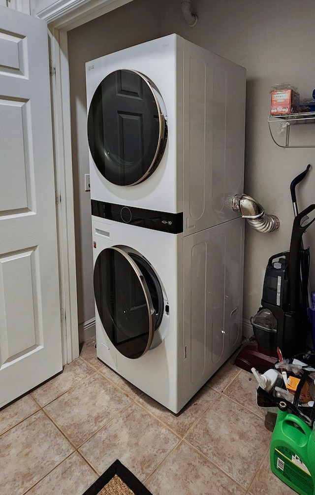 laundry area featuring laundry area, stacked washer / dryer, and light tile patterned flooring