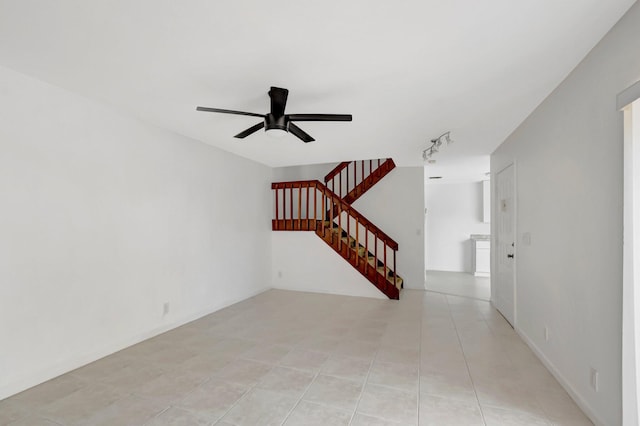 spare room featuring a ceiling fan, light tile patterned floors, and stairs