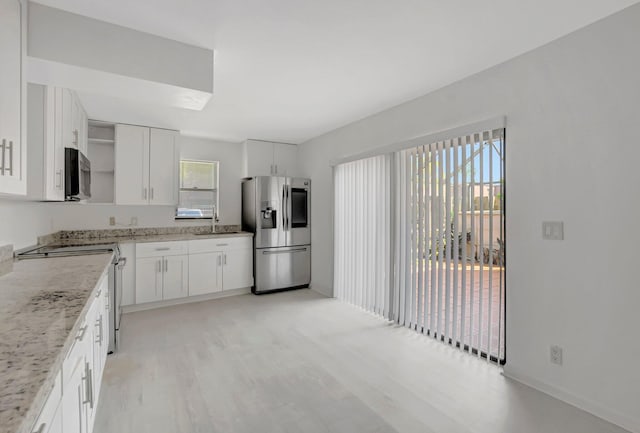 kitchen featuring a healthy amount of sunlight, appliances with stainless steel finishes, open shelves, and a sink