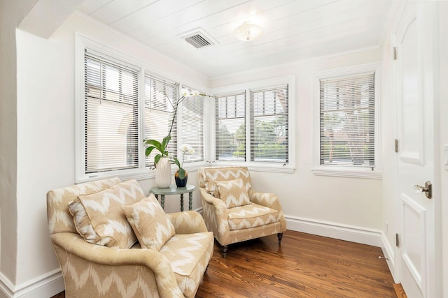 sitting room featuring baseboards, crown molding, visible vents, and wood finished floors