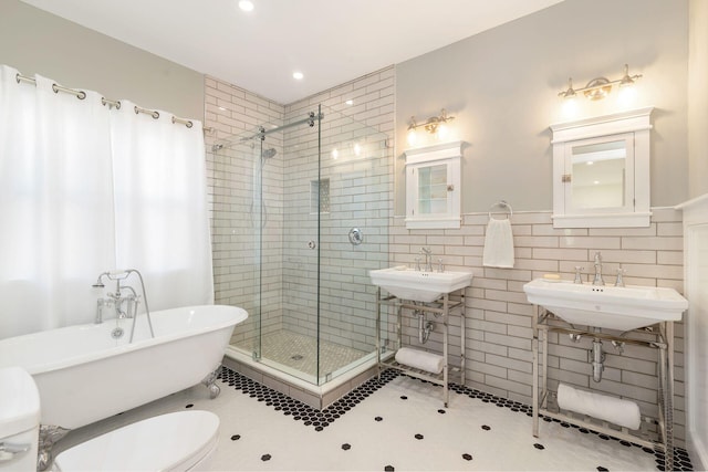 bathroom with a soaking tub, a shower stall, tile walls, and a sink