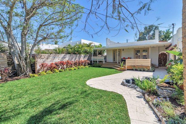 view of yard featuring fence and french doors