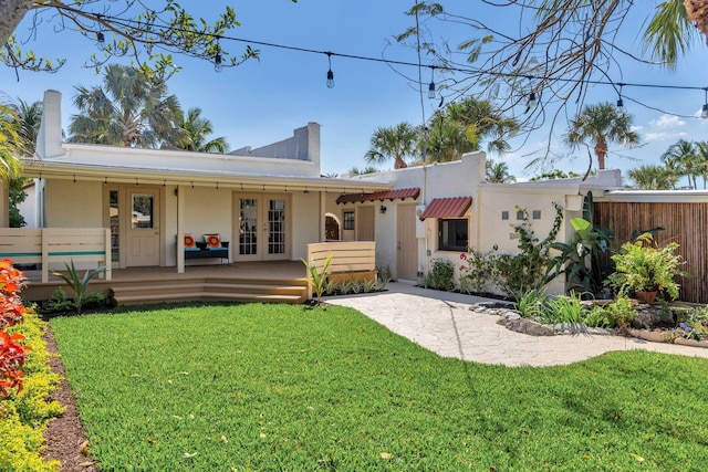 back of property with a yard, french doors, and stucco siding