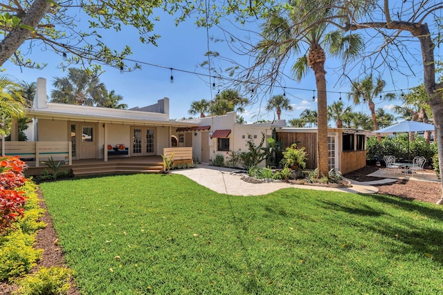 back of house with an outbuilding, french doors, stucco siding, a lawn, and a patio area