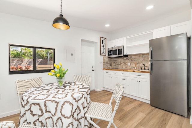 kitchen featuring white cabinetry, light wood-style floors, appliances with stainless steel finishes, backsplash, and open shelves