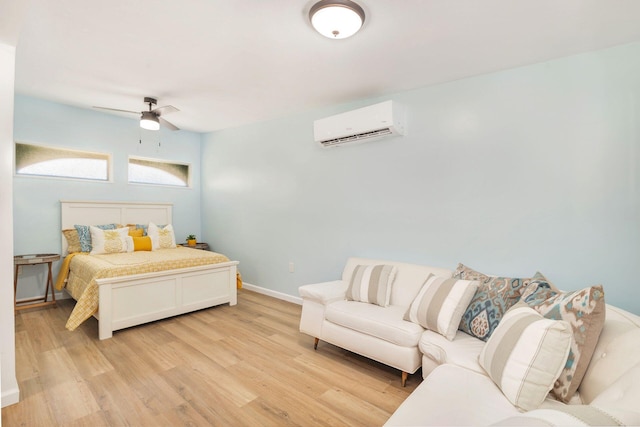 bedroom with light wood finished floors, ceiling fan, baseboards, and a wall mounted AC