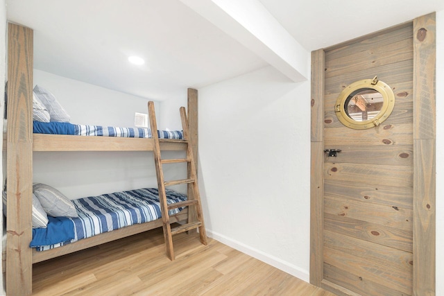 bedroom with wood finished floors, beam ceiling, and baseboards