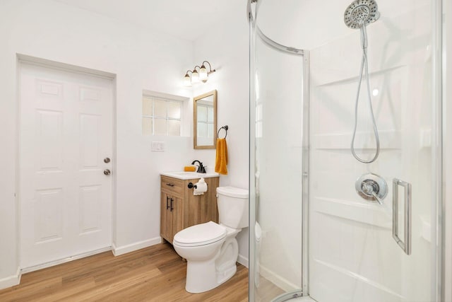 full bathroom with toilet, a stall shower, vanity, wood finished floors, and baseboards