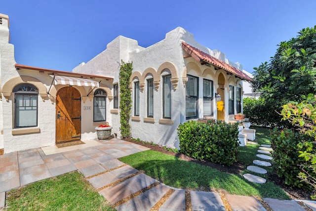 mediterranean / spanish house featuring a tiled roof and stucco siding