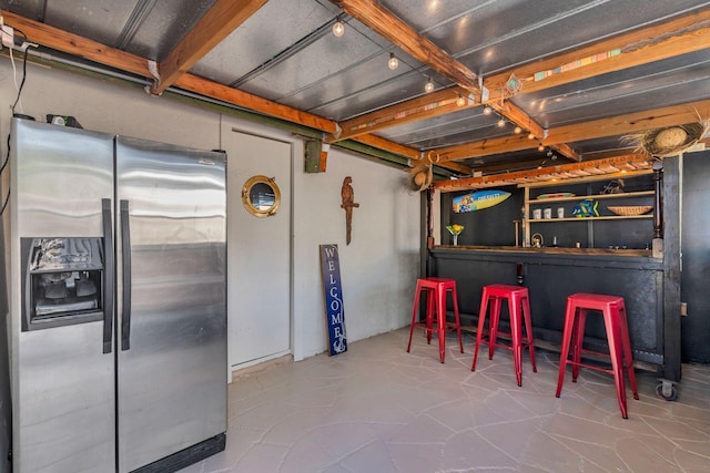 interior space with concrete flooring, stainless steel refrigerator with ice dispenser, and indoor bar