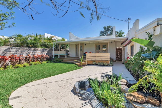 back of property with french doors, a yard, and stucco siding