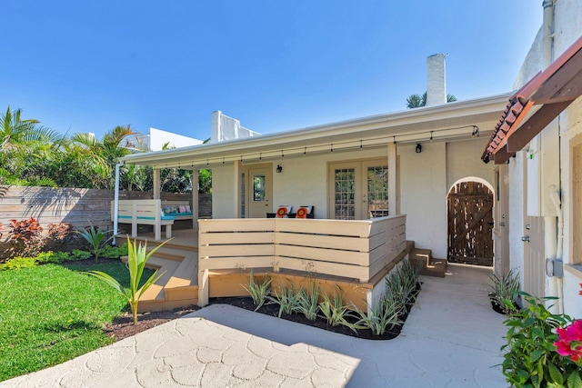 view of front of home featuring french doors, fence, and stucco siding